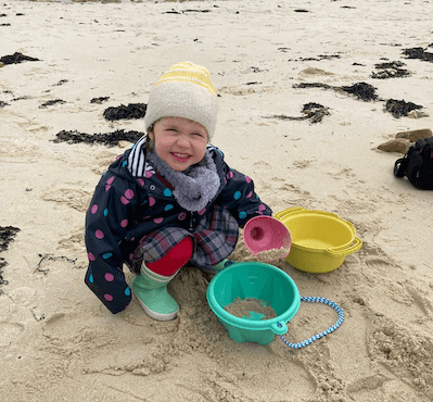 Une enfant sur la plage en train de jouer avec son kit de plage