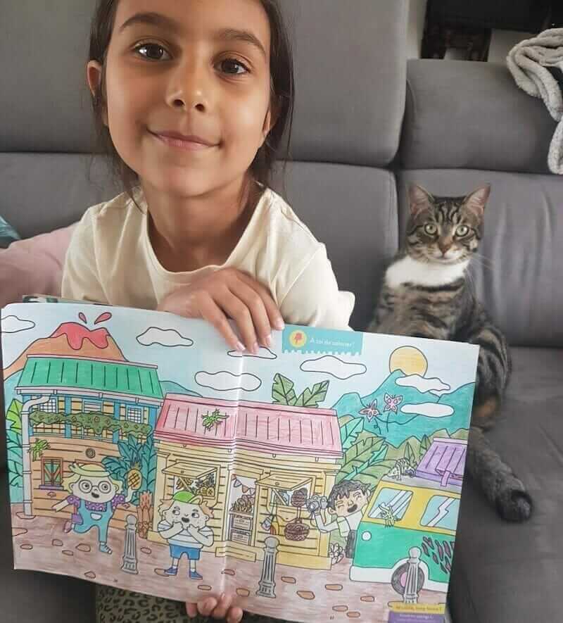 Une enfant abonnée montrant le coloriage qu'elle a réalisée dans son magazine Les Mini Mondes