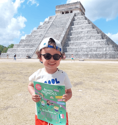 Un enfant abonné aux magazines Les Mini Mondes avec son carnet Mexique posant devant un temple Maya.
