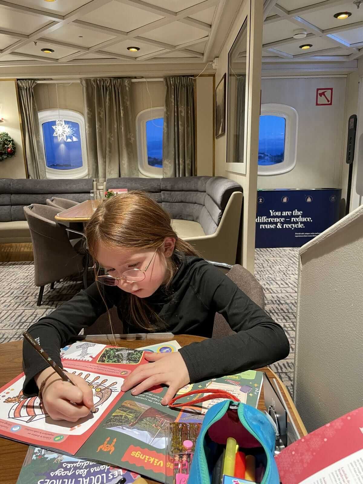 Océane, 6 ans, concentrée qui réalise un coloriage dans son magazine Les Mini Mondes