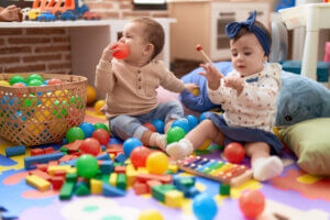 Deux jeunes enfants jouant avec des balles et un xylophone dans une crèche autour de Grenoble. L'environnement est rempli de couleurs pour encourager l'éveil.
