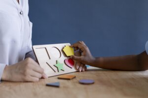 Enfant manipulant un puzzle sensoriel en bois pour apprendre les formes et les couleurs pour apprentissage multisensoriel.