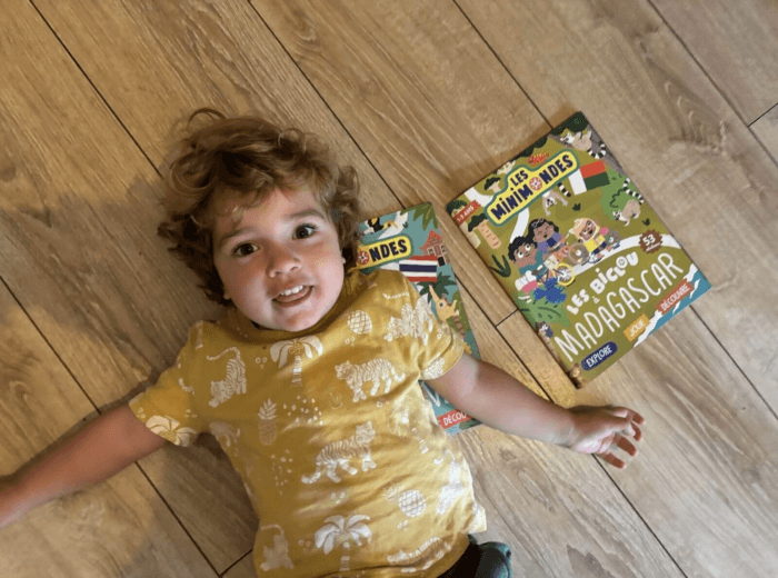 Enfant souriant lisant un magazine Les Mini Mondes
