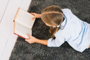 Enfant lisant un livre allongée sur un tapis, moment de lecture calme