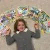 Fille de 5 ans allongée sur un tapis, entourée de plusieurs magazines éducatifs Les Mini Mondes sur différents pays